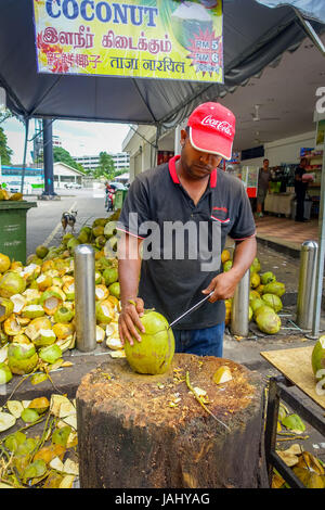 Kuala Lumpur, Malesia - 9 Marzo 2017: Sconosciuto venditore ambulante persona il taglio e la vendita di cocco fresco ai turisti. Foto Stock