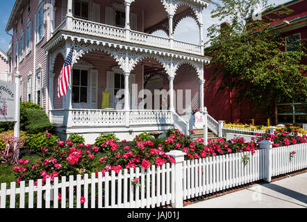 Casa vittoriana rosa, bandiera americana, recinzione di picket bianco, rosa scuro rose primavera giardino confine, Cape May, New Jersey, NJ, Stati Uniti, US, americano, 2017 US Foto Stock