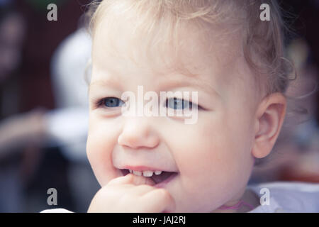 Carino affascinato sorridente bambina ritratto con il dito in bocca Foto Stock