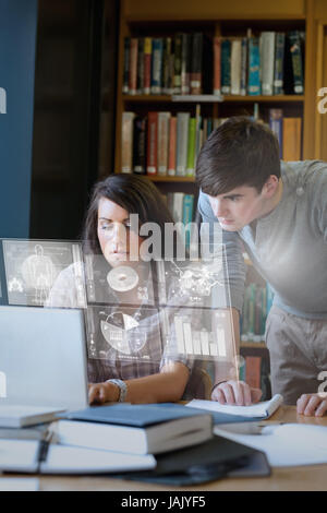 Seri studenti analizzando i grafici sulla loro interfaccia digitale nella biblioteca universitaria Foto Stock