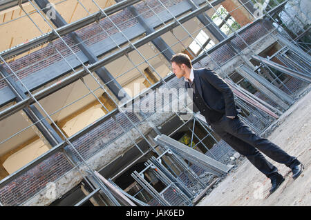 Junger Mann im dunklen Anzug auf einer Baustelle. Foto Stock