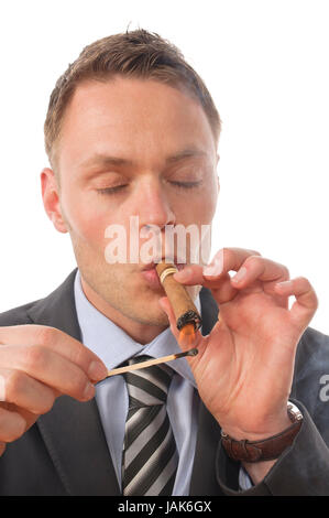 Junger Geschäftsmann in Anzug und Krawatte sitzt am Schreibtisch und genießt eine gute Zigarre aus seinem Humidor. Vor Freigestellt weißem Hintergrund Foto Stock