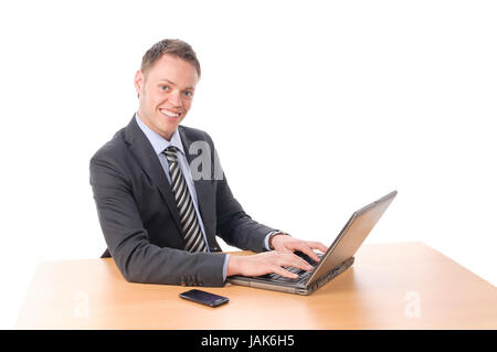 Junger Geschäftsmann in Anzug und Krawatte sitzt am Schreibtisch und arbeitet un Notebook seinem-PC. Vor Freigestellt weißem Hintergrund Foto Stock