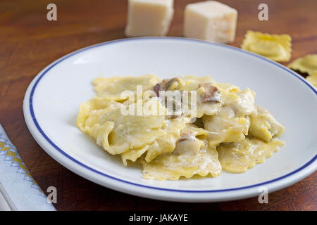 Piatto di ravioli con funghi e formaggio circondato da materie prime Foto Stock