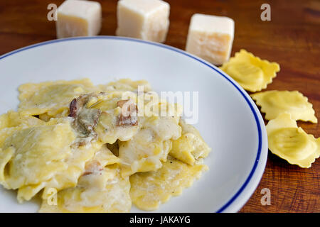 Piatto di ravioli con funghi e formaggio circondato da materie prime Foto Stock