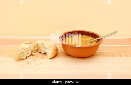 Ciotola di una deliziosa minestra di verdura con pane strappato a metà Foto Stock