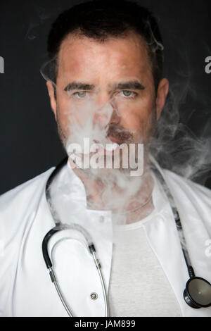Ritratto di bello medico fumatori e soffiare fuori il fumo Foto Stock