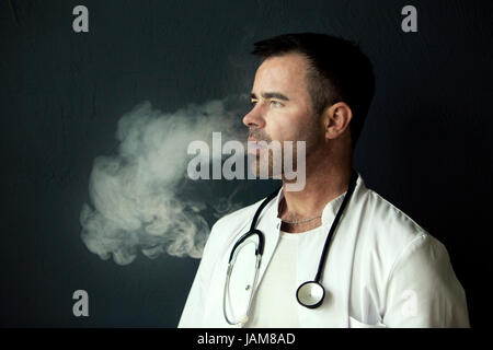 Ritratto di bello medico fumatori e soffiare fuori il fumo Foto Stock