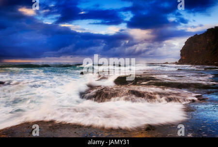 Nuvoloso maltempo lungo la costa del Pacifico in Australia in Sydney Nord spiagge Spiaggia Bungan inviando onde di rotolamento a terra. Foto Stock