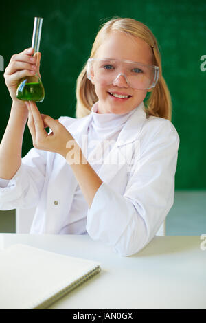Ritratto di carino schoolgirl tubo di contenimento con il liquido chimico e guardando la fotocamera Foto Stock