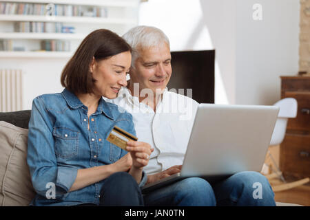 Coppia Matura collegato con il computer portatile e lo shopping online Foto Stock