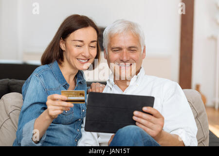 Coppia matura utilizzando la carta di credito per acquistare online Foto Stock