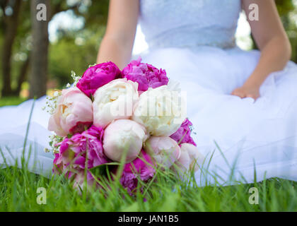 Sposa in un abito bianco con un mazzo di nozze Foto Stock