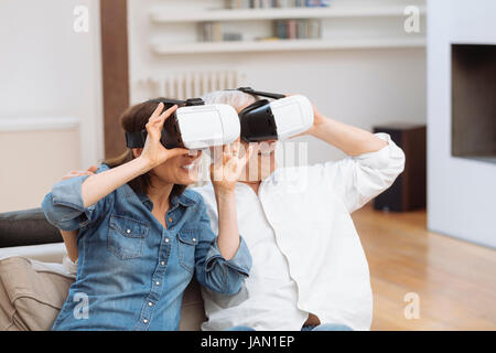 Coppia matura utilizzando la realtà virtuale auricolare in salotto Foto Stock