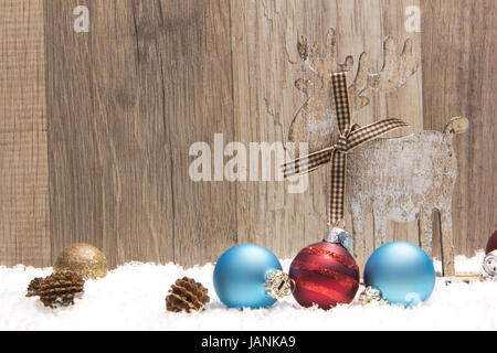 Decorazione di natale con uno sfondo di legno, neve elk, natale baubles oro, blu e rosso e pigne Foto Stock