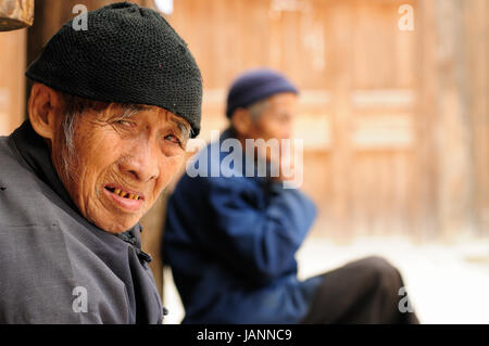 ZHAOXING, Cina - 11 novembre 2010: Cinese vecchia in appoggio sulla soglia del suo cottage nel villaggio Zhaoxing Foto Stock