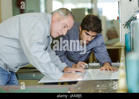 Carpenter piani e progetti scrive a disegni in officina Foto Stock