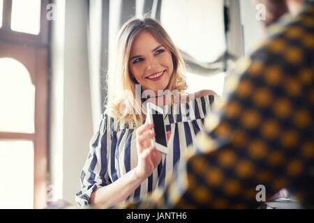 Femmina con il cliente utilizzando il telefono cellulare Foto Stock