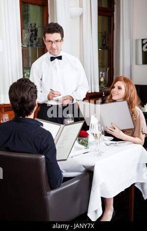 Frau und Mann beim Abendessen im Restaurant Kellner nimmt Bestellung auf Foto Stock