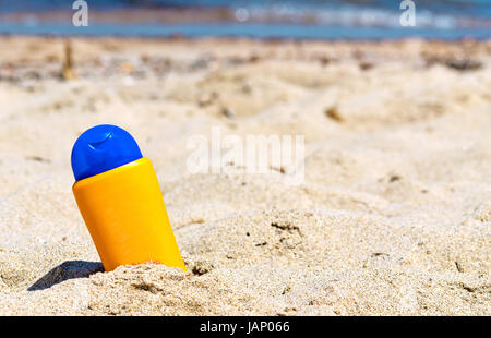 Creme abbronzanti bottiglia bloccato nella sabbia Foto Stock