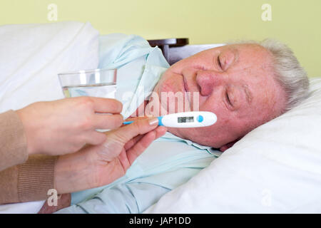 Immagine di un vecchio e malato uomo a letto con la febbre Foto Stock