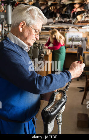 Calzolaio, uomo tirando le unghie con pinze fuori dello scorso, sul retro donna al tavolo di lavoro, Kainisch, Stiria, Austria Foto Stock