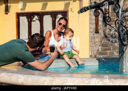 Una famiglia pone per le foto alla fontana Ippokratous, Rodi Città Vecchia, Rodi, Grecia Foto Stock