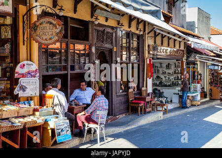 Uomo greco Sit in chat al di fuori di un cafè sulla Sokratous Street, Rodi Città Vecchia, Rodi, Grecia Foto Stock