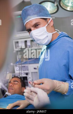 Medico chirurgo in possesso di una forbice durante un'operazione Foto Stock