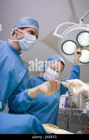 Il team di chirurgia di lavorare sotto le luci chirurgico Foto Stock