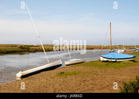 Piccole barche sulle rive fangose del canale New Cut attraverso le paludi saline che conducono al Blakeney Quay nel Nord Norfolk. Foto Stock