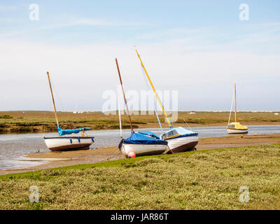 Piccole barche sulle rive fangose del canale New Cut attraverso le paludi saline che conducono al Blakeney Quay nel Nord Norfolk. Foto Stock