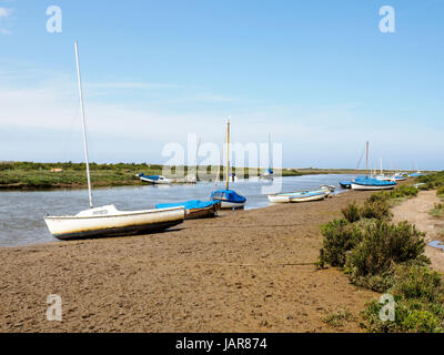 Piccole barche sulle rive fangose del canale New Cut attraverso le paludi saline che conducono al Blakeney Quay nel Nord Norfolk. Foto Stock