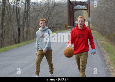 Identici fratelli gemelli giocare a basket in strada Foto Stock