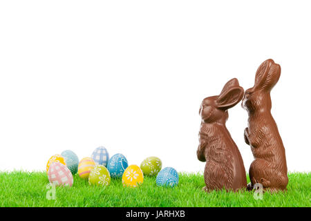 Paio di cioccolato conigli pasquali con uova colorate su un prato. Foto Stock