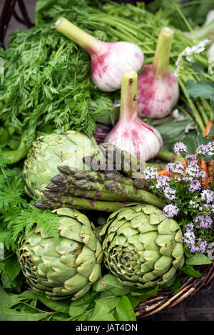 Cesto di appena raccolto le verdure compresi i carciofi, aglio e gli asparagi in una serra, REGNO UNITO Foto Stock