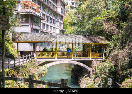 JIANGDI, Cina - 26 Marzo 2017: turisti sul ponte sulla gola con creek vicino a spa resort hotel di Longsheng Hot Springs National Forest Park di Xian Foto Stock