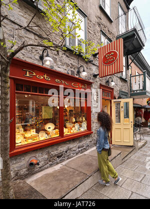Una giovane donna in piedi di fronte a Pot en Ciel store su Rue Petit Champlain strada storica nella Vecchia Quebec City e guardando il suo colorato display win Foto Stock