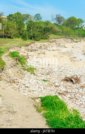 Spiaggia di erosione. Erosione ha rimosso grandi parti del suolo nel mare, lasciando le pietre e ripide coste. Foto Stock