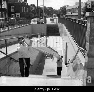 Terry Bell, 24-anno-vecchio giornalista e il suo insegnante moglie Barbara, 27, portando loro 16ft in fibra di vetro Amandhla canoa dalla metropolitana sotto la Cromwell Road estensione come essi lo prese dalla loro casa a Chiswick High Road, Londra, al fiume Tamigi per una prova finale. Essi hanno intenzione di avviare sguazzare nelle loro canoe dal Tamigi il 21 agosto sul primo piedino di un 7.000 miglia di viaggio a Dar es Salaam, Tanzania. Foto Stock