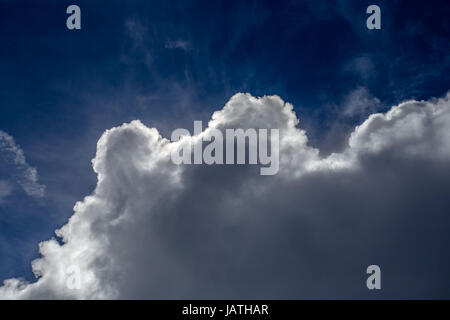 Sun nascondersi dietro a nuvola in cielo blu Foto Stock