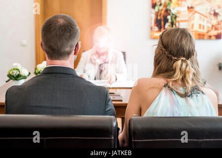 I giovani sposi novelli sposi seduti insieme davanti al matrimonio del cancelliere Foto Stock