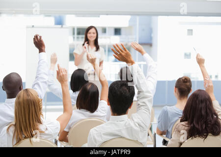 Pubblico alzando le mani mentre si guarda un imprenditrice Foto Stock