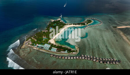 Piccola isola delle Maldive con tipici villaggi e bungallow su di esso. La foto è stata scattata dal piano. Foto Stock