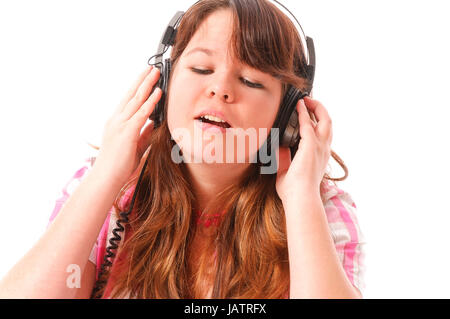 Junges mMädchen mit langen Haaren dunklen hört mit Begeisterung Musik Mit einem vor Kopfhörer weißem Hintergrund. Foto Stock