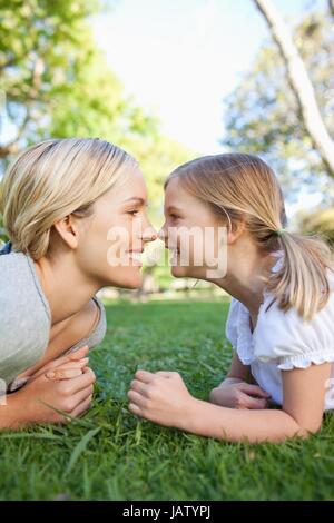 Una madre e figlia rub nasi sdraiati sull'erba Foto Stock