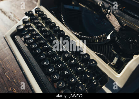 Foto della vecchia macchina da scrivere sul tavolo di legno nella luce del tramonto, look rétro. Foto Stock