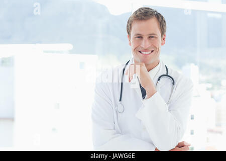 Medico sorridente in piedi accanto a una finestra Foto Stock