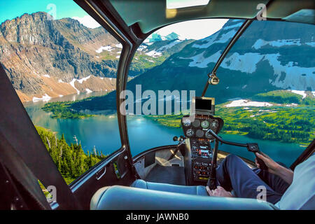 Elicottero cockpit con braccio di pilota e la consolle di comando in cabina volo sulla spettacolare vista aerea nascosta del lago si affacciano nel Glacier National Foto Stock