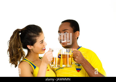 QUITO, ECUADOR - 06 Maggio 2017: giovane coppia ecuadoriana indossando maratona ufficiale Football Shirt in piedi di fronte alla fotocamera, la condivisione di un bicchiere di birra con il suo fidanzato, sfondo bianco Foto Stock